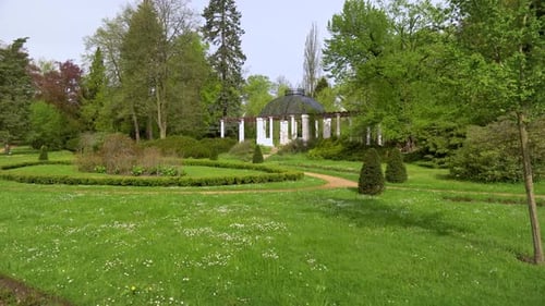 beautiful european garden with tidy beds and a summer house on a sunny day