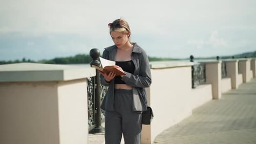 Stylish Woman Reading a Book on City Walkway