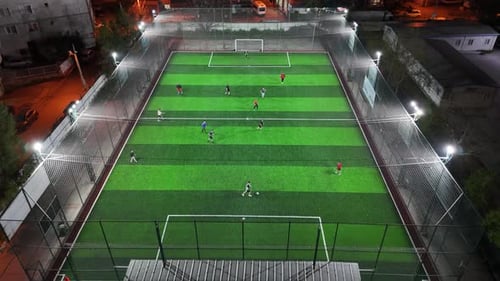 Aerial Drone View of Football Field at Night with Stadium Lights