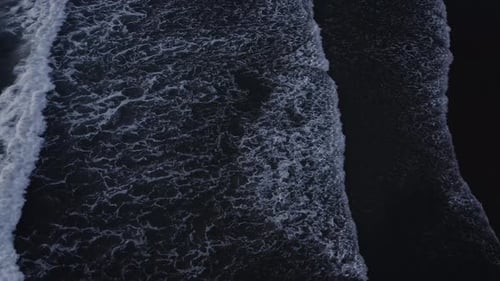 Aerial View of Waves Crashing on Dark Beach