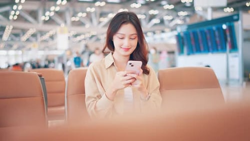 Asian tourist woman using mobile phone between waits for flight in Airport Terminal