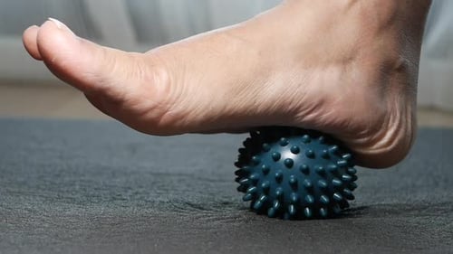 Woman Rolls Foot on Spiky Ball for Plantar Fasciitis