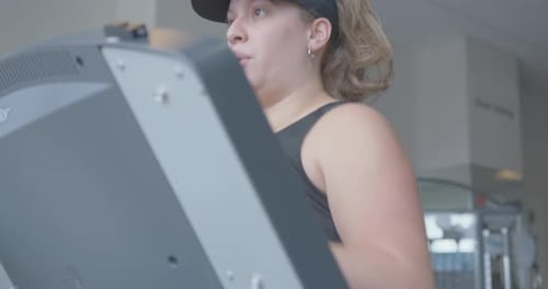 Close Up Tilt Up of a Young Jogging on a Treadmill