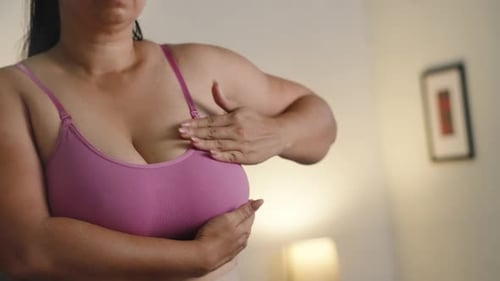 Adult Hispanic woman performing a self-examination. Cancer awareness, early detection, prevention.