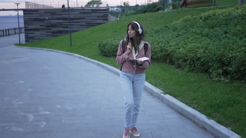 Student Walking and Taking Notes in a Park