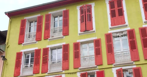 Vibrant building with yellow walls and red shutters in Vizille France on a sunny day