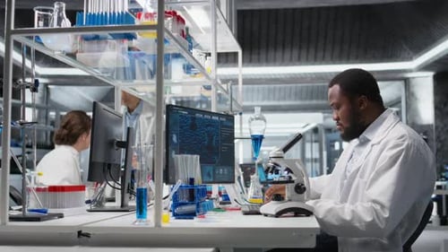 Scientist Using Microscope in Lab with Colleagues