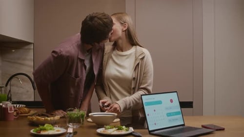 Young Couple Kissing While Preparing Food at Home