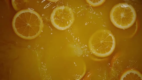 Orange Slices Splashing into Orange Juice