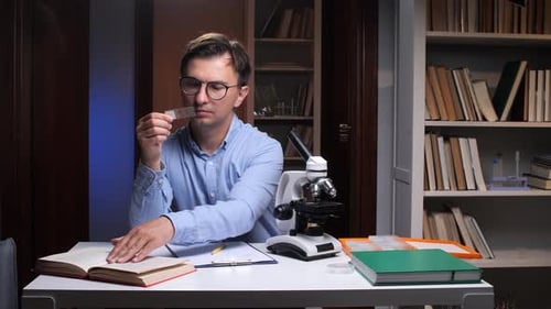 Scientist Examining Microscope Slide in Laboratory Setting