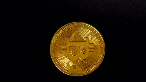 Golden Bitcoin displayed against a dark black background, showcasing intricate details of its engrav