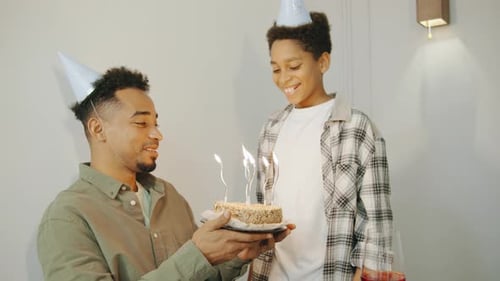 A Small Boy Surprises His Father with a Festive Birthday Cake Topped with Candles The African