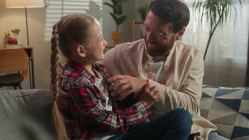 Father and Daughter Laughing and Playing on Sofa