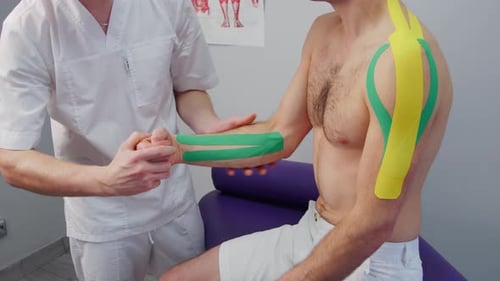 Physical Therapist Treating Man's Arm With Tape