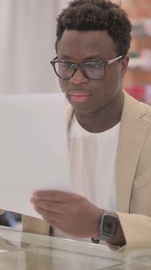 Young Adult Reading Documents in Workplace