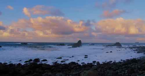 Slow motion of ocean waves crashing on volcanic rocky shore. Sunset wavy seascape at tropical paradi
