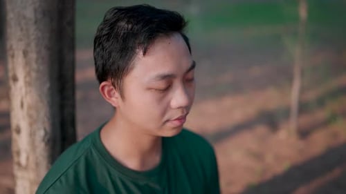 Close-up of a man meditating to relax and calm his mind after a stressful day at work in a park in t