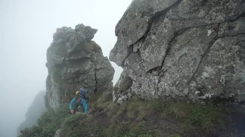 Un homme avec un sac à dos grimpe les montagnes Rocheuses dans le brouillard