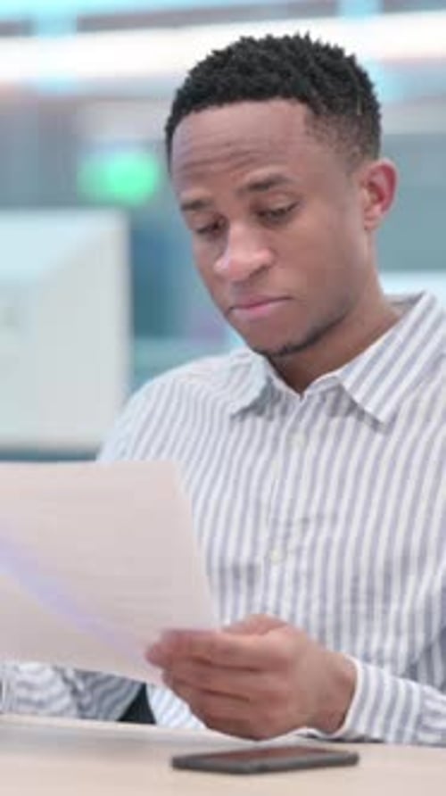 African Businessman Reading Documents in Office, vertical video