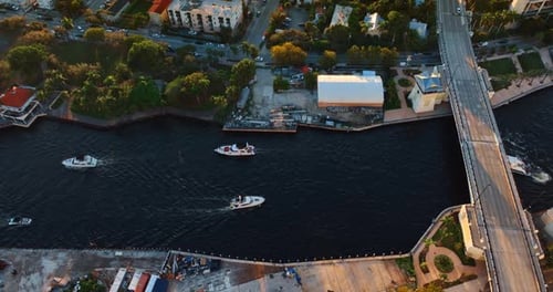 Four boat move slowly by the river near the bridge. Drone approaching one of the vehicles in Miami