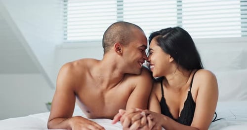 Romantic Couple Holding Hands and Smiling in Bed