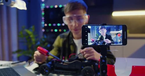 Teen repairs toy car, recording video at home