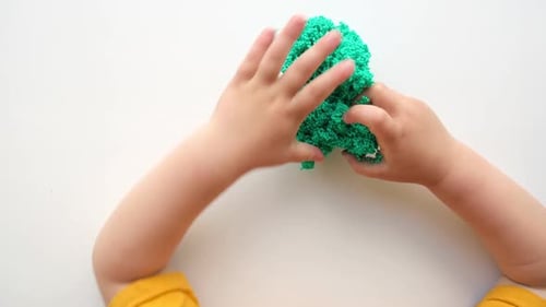 Baby Hands Playing with Textured Slime with Bubbles Stretching the Gooey Substance on White