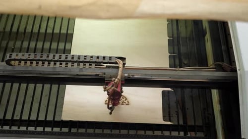 An Industrial Laser Cuts a Pattern on a Sheet of Plywood A Red Laser Beam