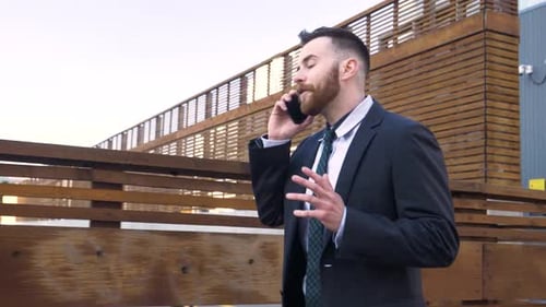 Businessman in Suit Walking and Talking on Smart Phone in City Adult