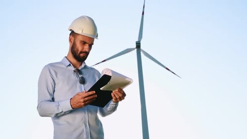 Vor blauem Himmel, Notizblock in der Hand. Servicetechniker ist mit Windmühlen vor Ort