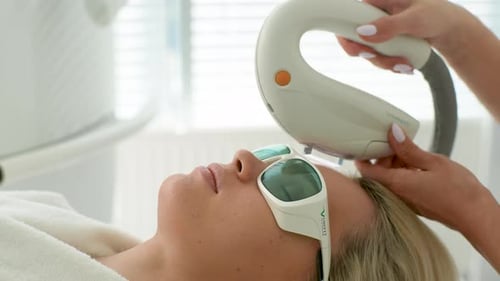 Closeup Side View of Blonde Young Woman with Protective Glasses Getting Photo Rejuvenation Procedure