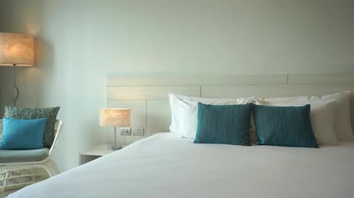 A tropical themed hotel room with ocean highlight and neutral colors has a large and inviting bed. F