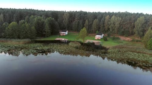 Cabin Houses By The Lush Forest Near The Calm Lake In Rogowko, Poland. - aerial drone shot