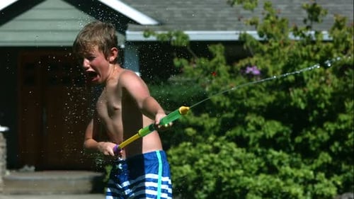 Enthusiastic Boy Playing with Water Gun Outside