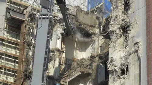 Excavator Demolishing Old Building With Workers Spraying Water.