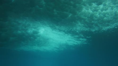 Rise up from underwater ocean surface with storm cloud patterns of whitewash on water