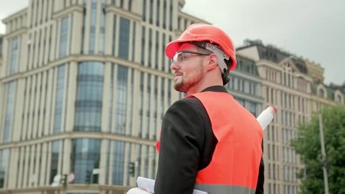 Construction Engineer Holding Blueprints Near Urban Building