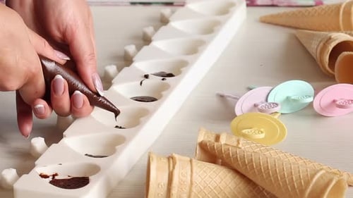 Eine Frau füllt flüssige Schokolade in eine Silikonform. Macht Zuckerguss für hausgemachtes Eis. Nahaufnahme