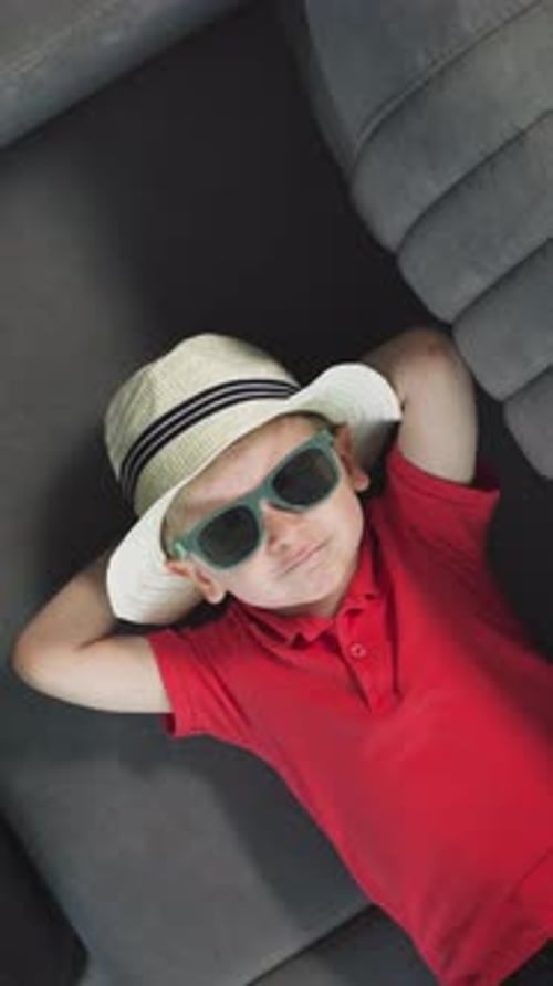 Stylish Child Lying on Couch with Sunglasses