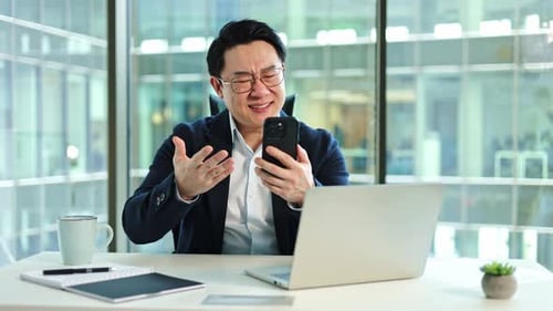 Stressed Businessman Reacts to Bad News on Phone in Office