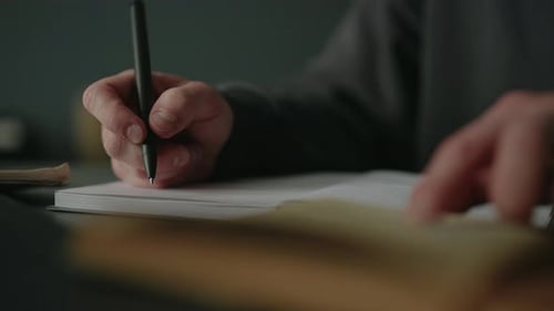 Die Schüler schreiben Notizen mit Stift in das Notizbuch, während sie zu Hause aus dem Lehrbuch lernen, konzentriert sich auf