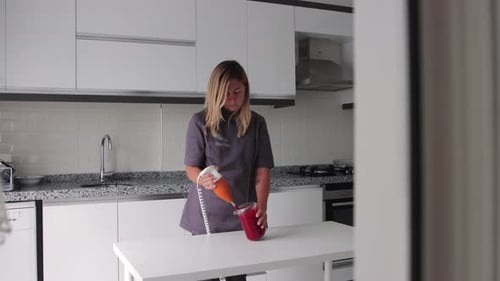 Woman Blending Drink with Immersion Blender in Kitchen