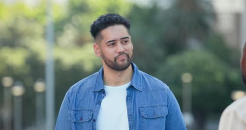 Zwei Männer unterhalten sich auf dem Platz mit Laternenpfählen, ein in Denim gekleideter Mann reagiert, als ein Afroamerikaner eintritt