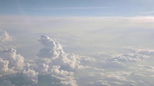 Airplane flying above clouds with a blue sky over the horizon