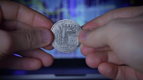 Bitcoin Close Up Held in Hand Before Laptop