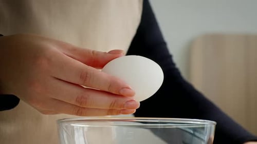 Der Koch bereitet eine gesunde Mahlzeit zu, indem er ein Bio-Ei in eine Glasschale knackt