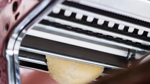 Woman Using Pasta Machine to Make Fresh Pasta Dough in the Kitchen Cooking in Italian Restaurant