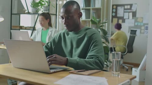 Young Black Man Working on Laptop in Open Space Office
