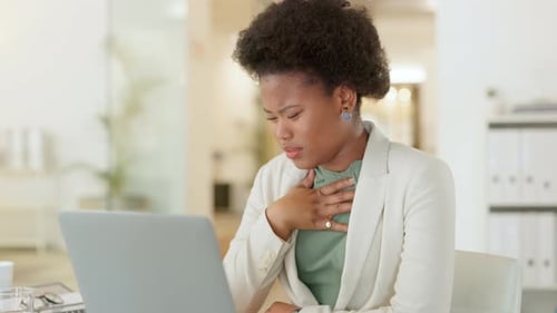 Sick businesswoman with afro coughing, suffering from coronavirus and using laptop