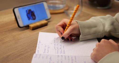 Hand of Young Girl Take Note From Electronic Textbook to Copybook